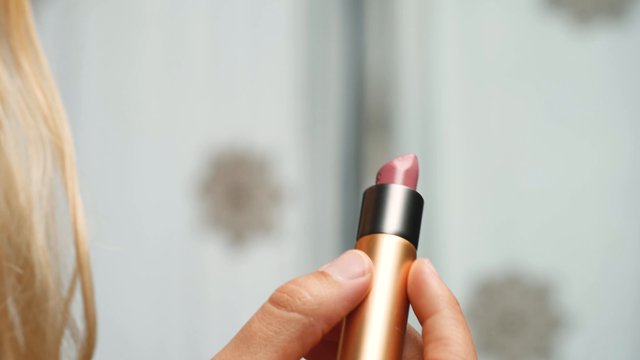Applying pink lipstick