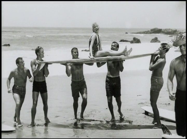 Young surfers gather on a sunny beach in this mid-century montage, showcasing recreational beach activities and the classic surf aesthetic of the era.