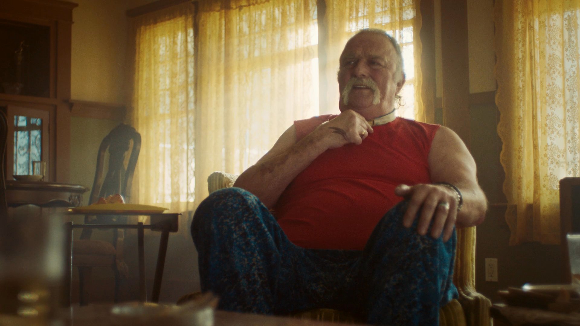 Three individuals engage in an intense, intimate conversation within a living room setting, characterized by thoughtful expressions and verbal exchanges.