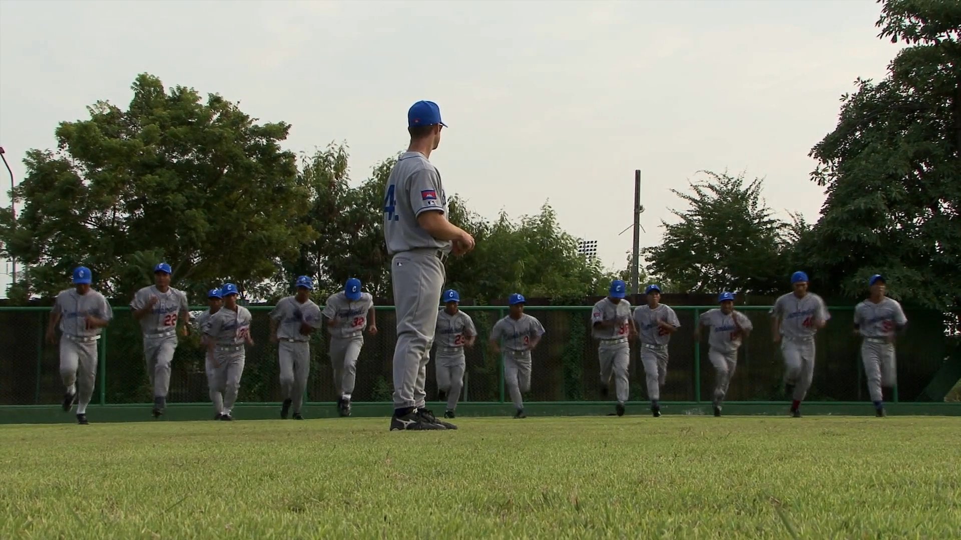 Members of a baseball team travel by bus before arriving at a field to conduct warm-up exercises and practice routines.