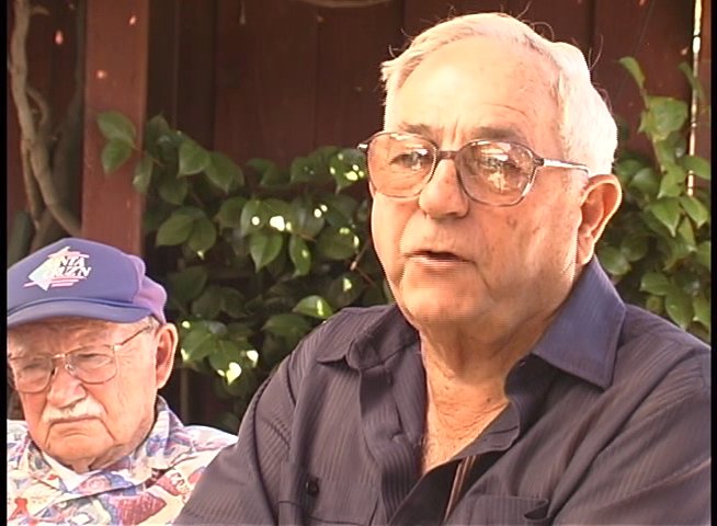 An elderly veteran recounts past experiences through a candid interview, with visual overlays of archival historical footage illustrating his memories.