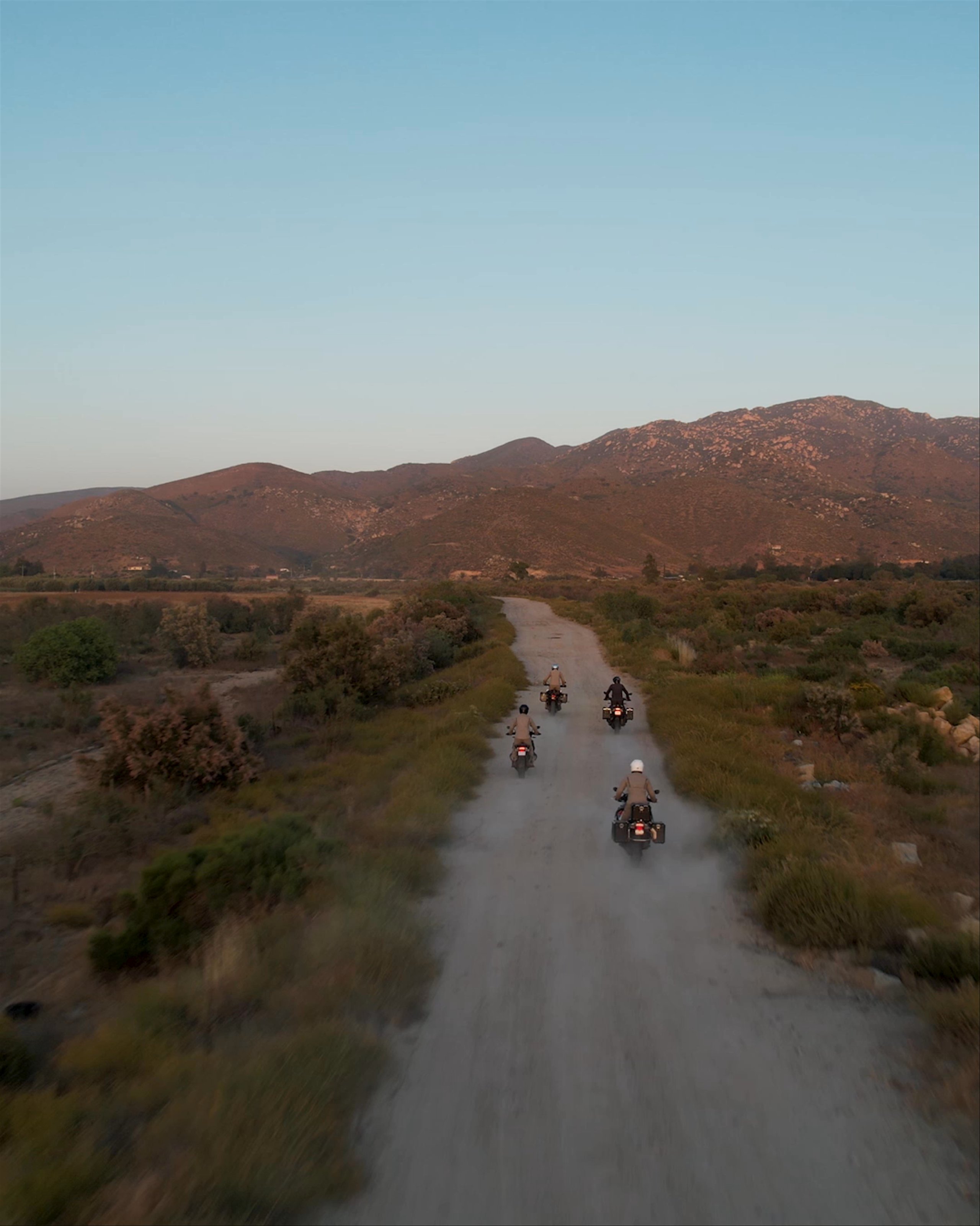Group of motorcyclists riding down dirt path in Baja California