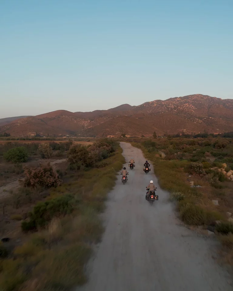 Group of motorcyclists riding down dirt path in Baja California
