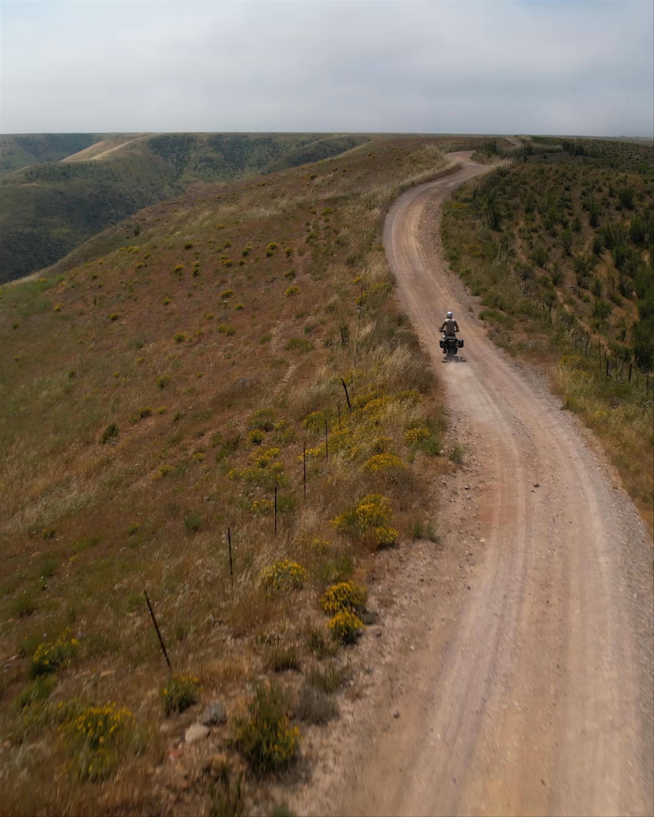 Motorcyclist riding up dirt path up mountainside in Baja California