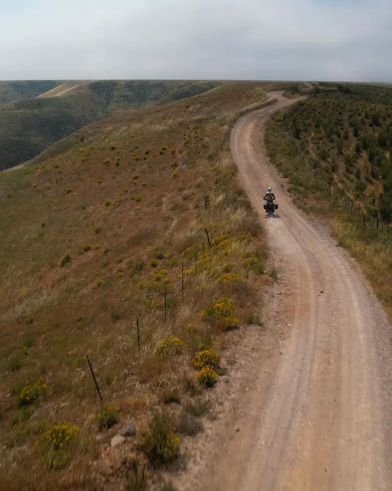 Motorcyclist riding up dirt path up mountainside in Baja California