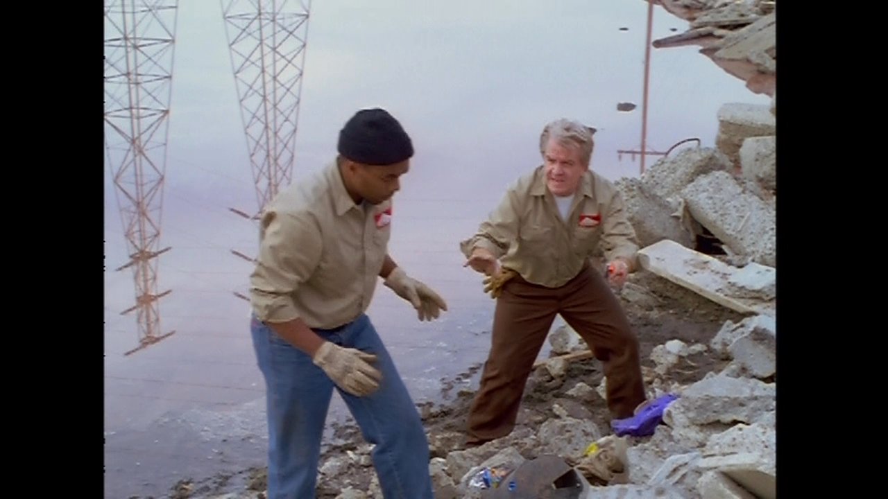 An office-bound individual discusses project details while laborers perform debris cleanup on an industrial waterfront location.