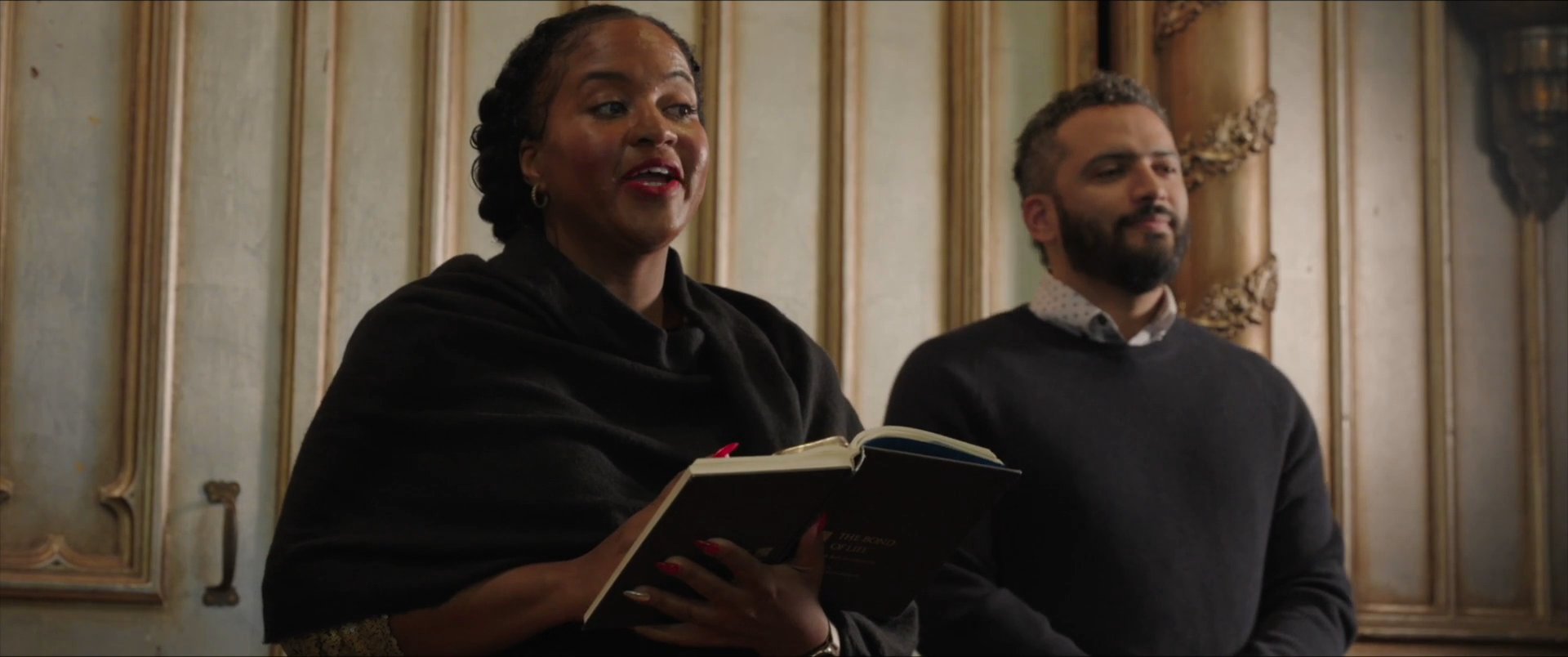A diverse choir ensemble performs a collective song within a traditional church interior. The participants sing with focused expressions, demonstrating musical coordination and community engagement.