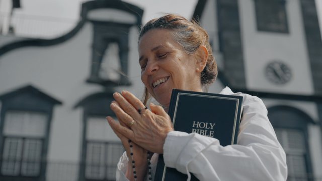 A smiling woman prays near a church