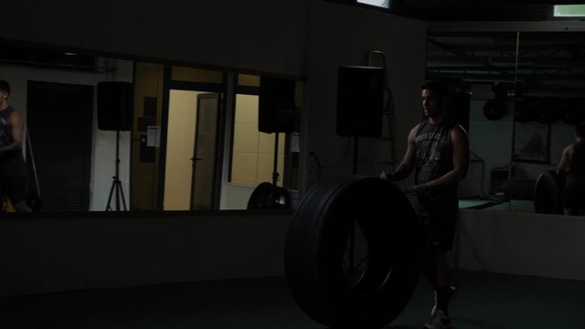 Man rolling a tire in the gym