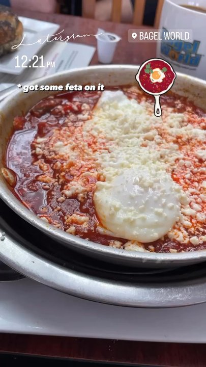 Bagel World - Shakshuka with feta cheese with poppy seed bagel and coffee in the background. July 2023 - Bagels Near Me - Toronto, Ontario