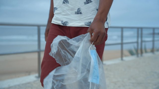 A guy carrying rubbish while walking down the quay.