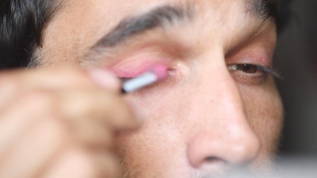 Man applying pink eyeshadow