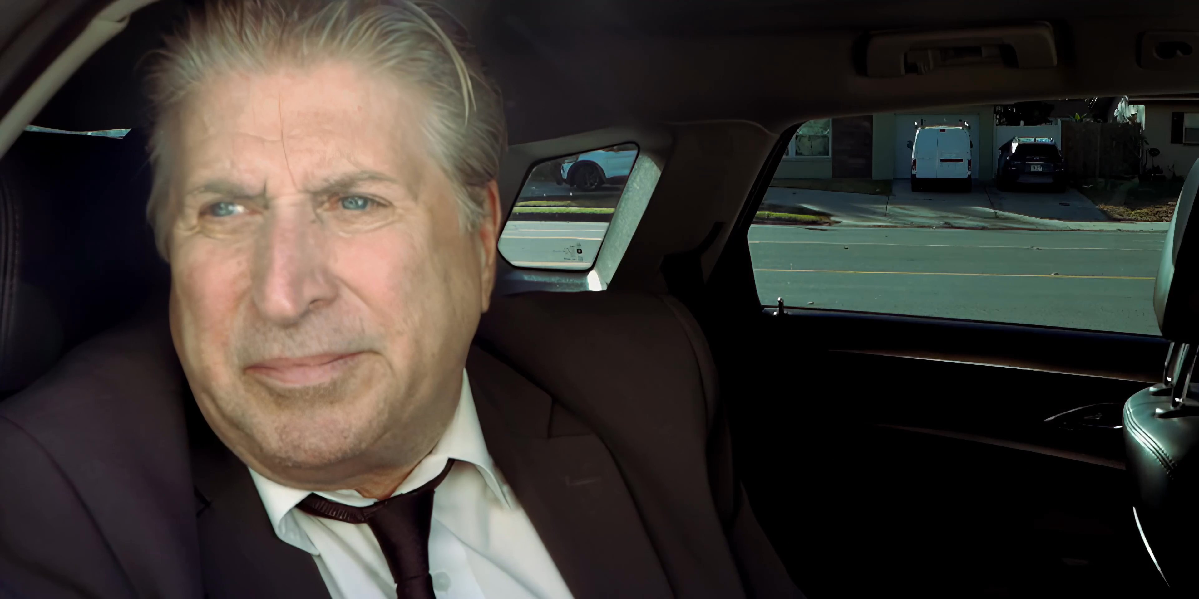 Two men engage in a serious, focused conversation while sitting inside a car. They exchange viewpoints during a commute, emphasizing a collaborative or professional dialogue.