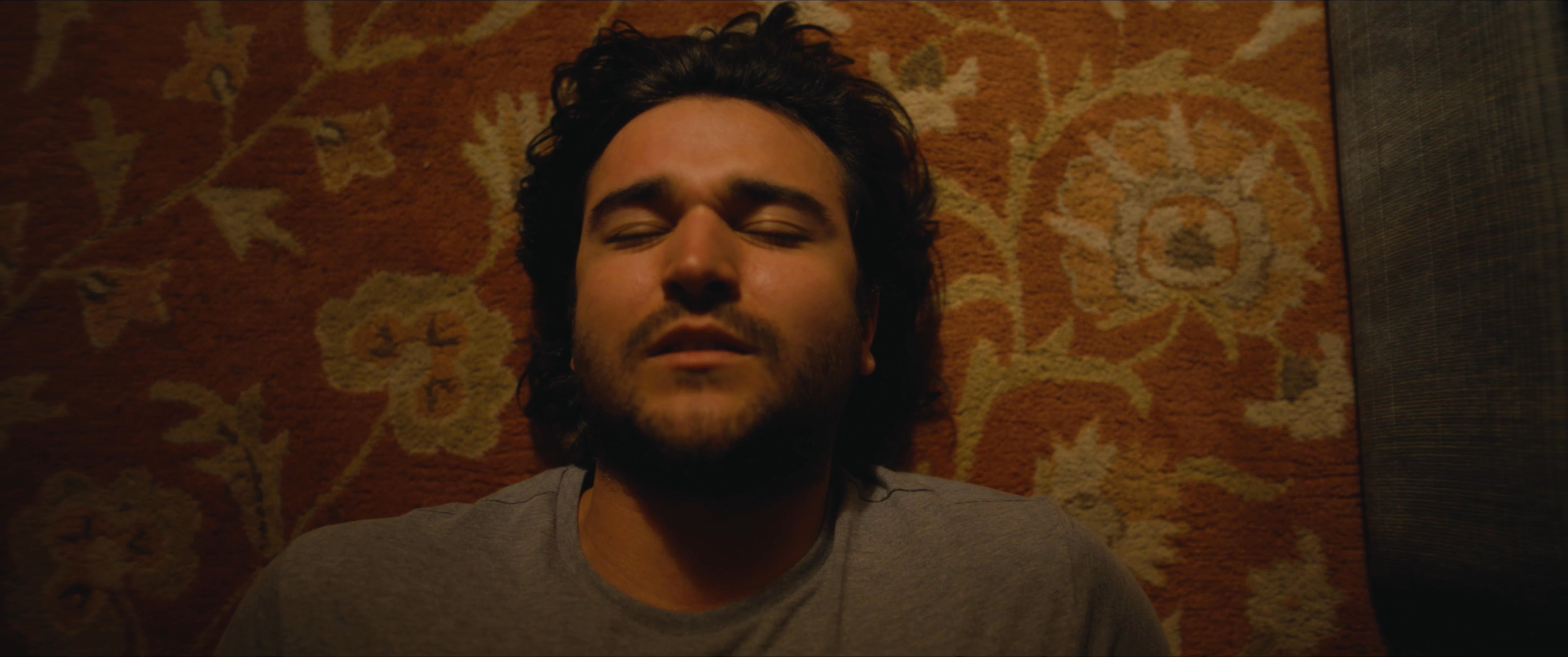 A man lies on his living room floor, transitioning into a vivid flashback of himself in full combat gear on a dark, foggy battlefield.