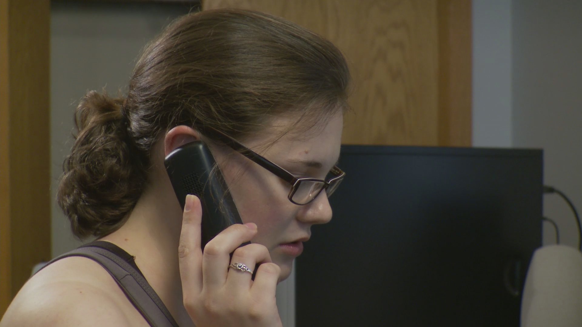 An older man and a young woman conduct a phone conversation, alternating dialogue while focused on their discussion.