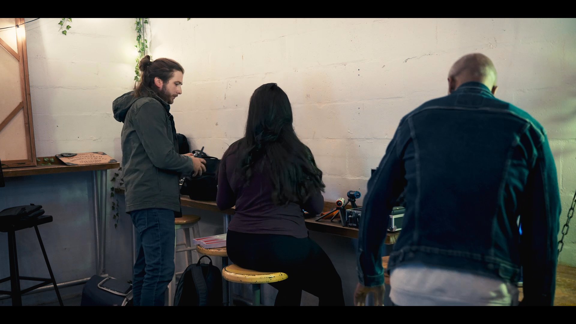 A diverse team gathers in a workspace to coordinate activities using handheld devices and laptop technology. The group communicates and synchronizes their efforts in a professional setting.