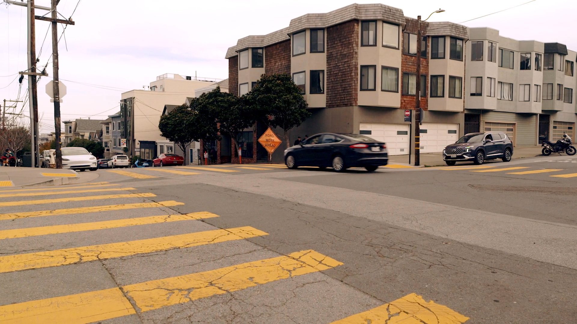 Aerial perspectives of San Francisco transition into a street-level view of a man commuting in his vehicle, followed by a professional meeting at an outdoor cafe.