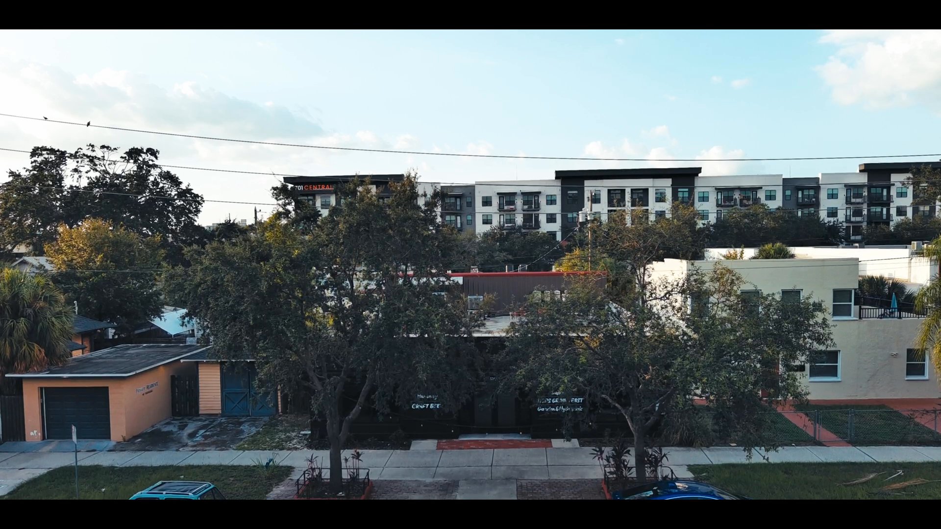 A man drives through a city followed by an aerial transition to a social gathering of women inside a modern restaurant bar.