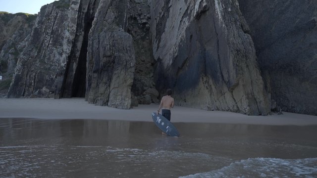 A man walking along a shore with his surfboard