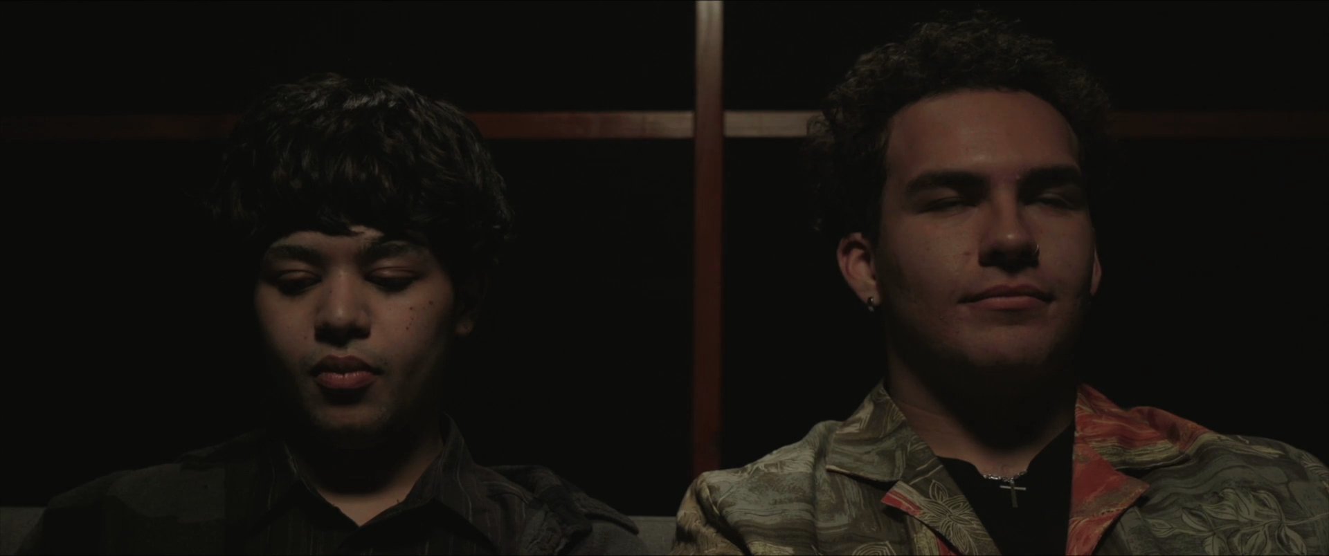 Two individuals engage in a focused conversation within a dimly lit setting. The scene transitions to both participants viewing a screen, suggesting a collaborative or analytical exchange.