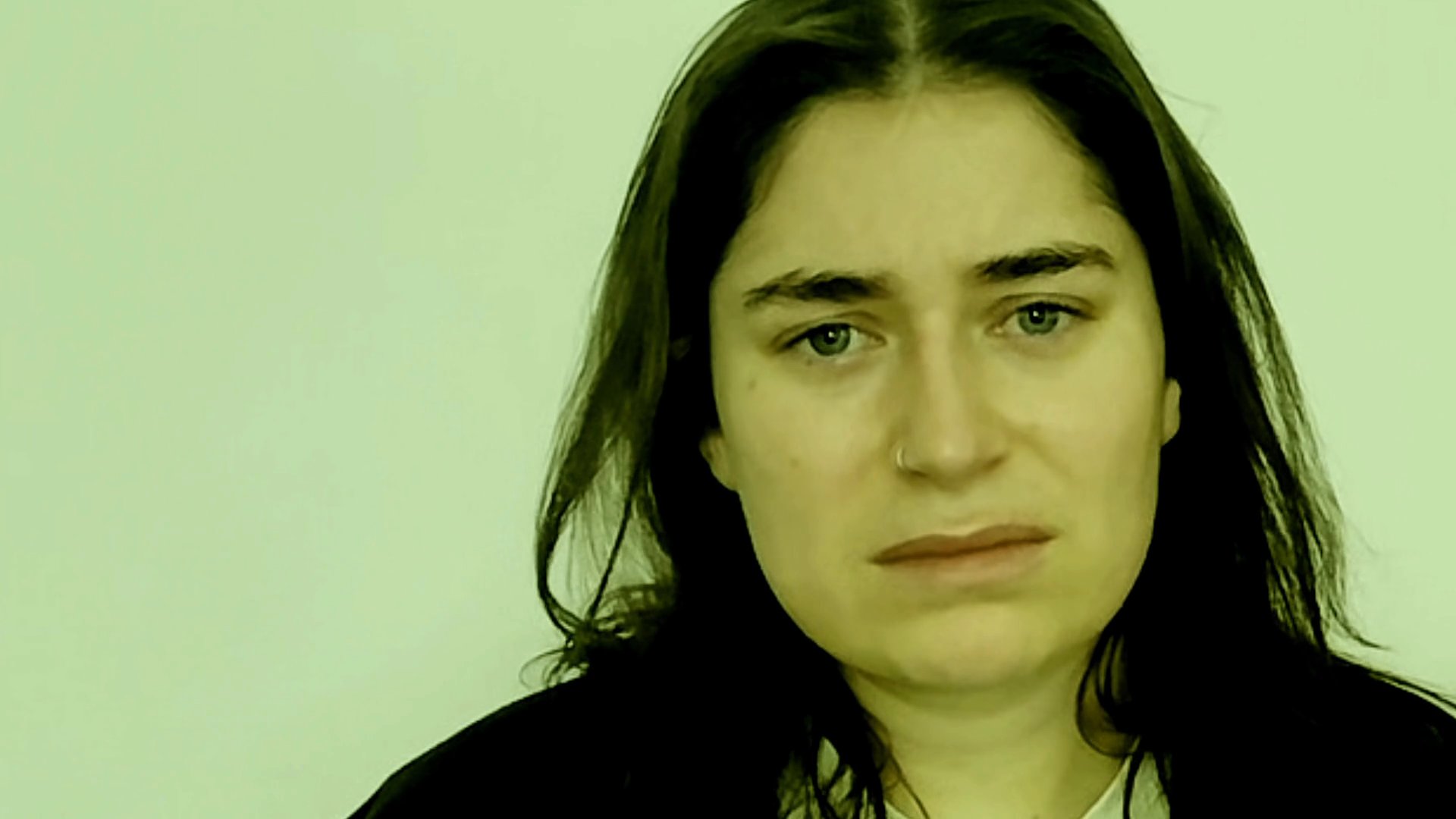 A woman performs a heartfelt monologue, exhibiting a range of emotive facial expressions and vocal delivery in a studio setting.