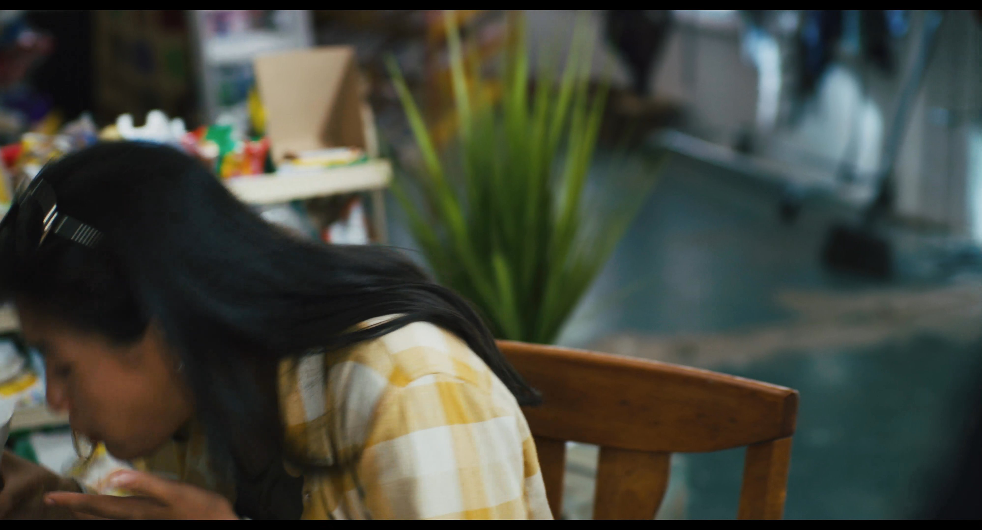 A man in work apparel speaks to a visibly distressed woman sitting in a convenience store, leading to an emotional confrontation. The woman attempts to compose herself with a beverage before wiping away tears with a tissue.