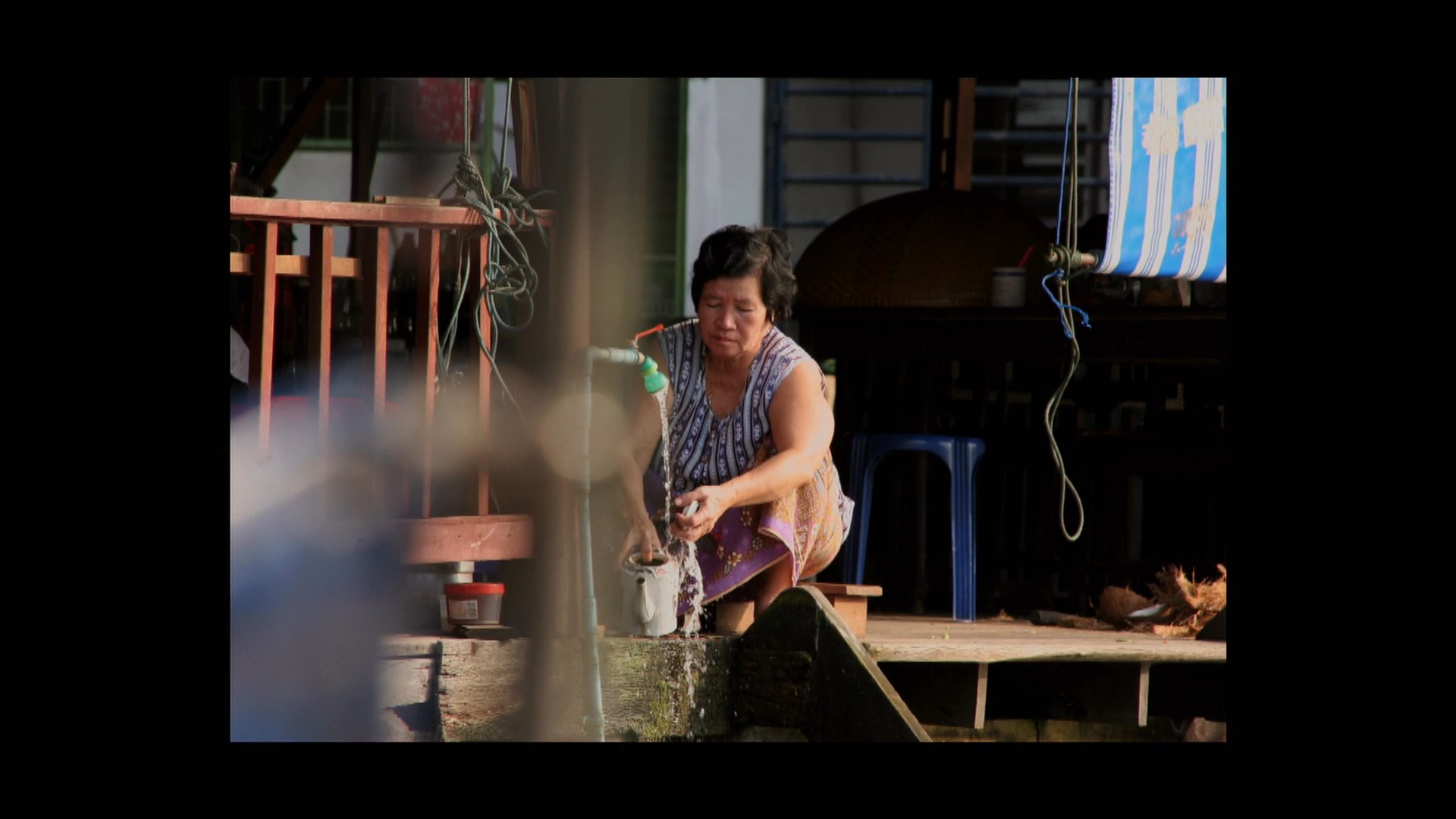 The sequence highlights urban river transit in Bangkok, contrasting waterfront dwellings and local activity with a traveling group associated with the Cambodia Baseball Federation.