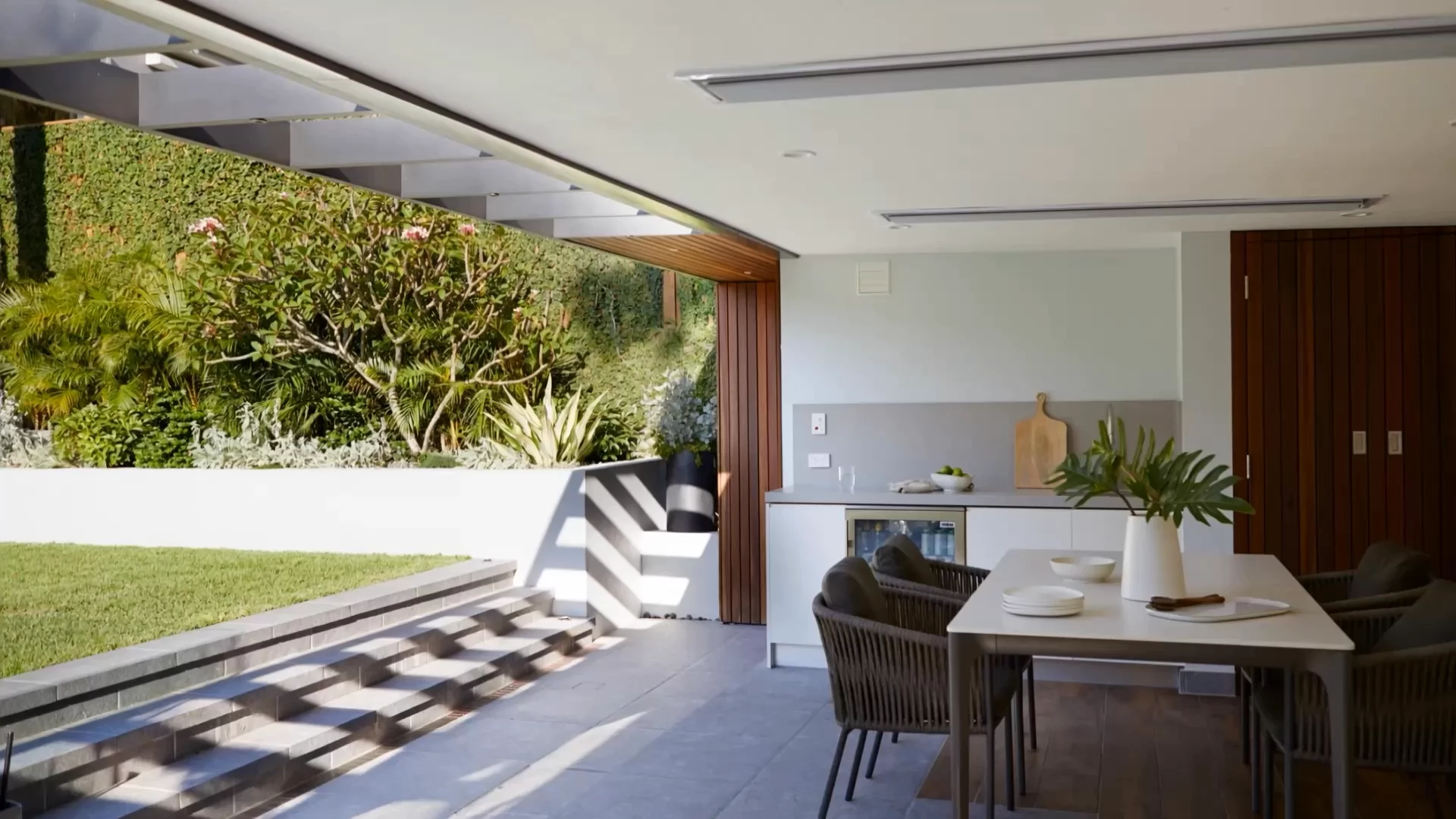 A designed coastal Sydney garden at golden hour — sandstone path through layered planting to a modern pavilion
