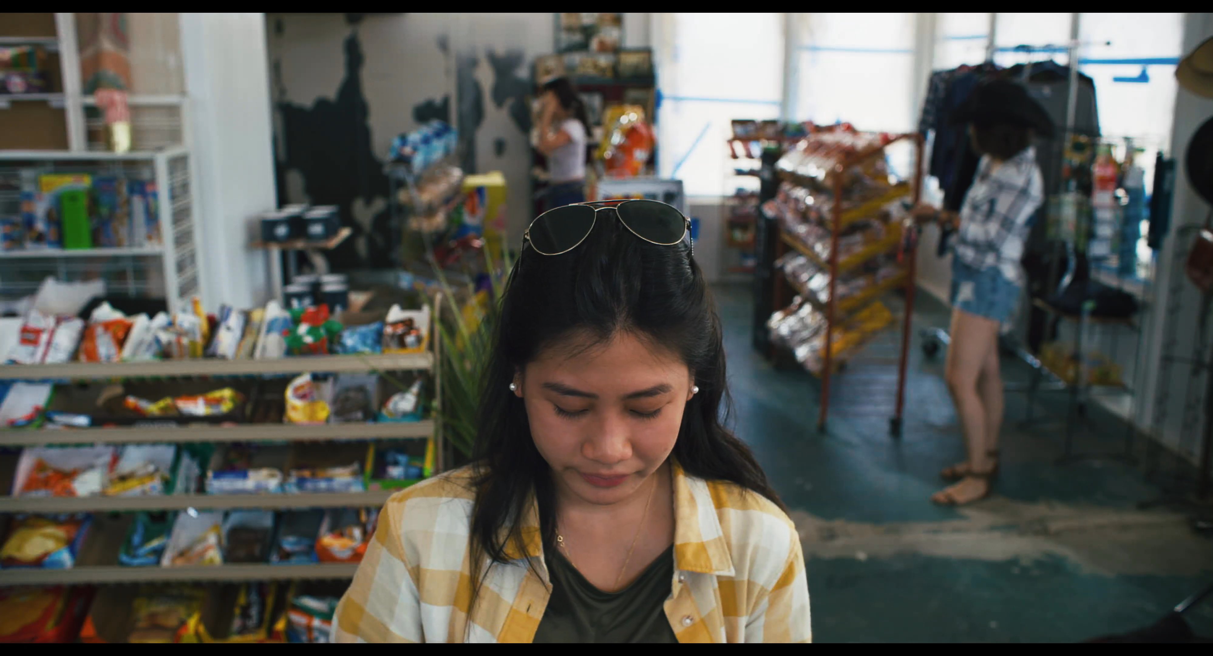 A customer pays a convenience store clerk for her purchase at the service counter. The clerk, wearing a Seahawk-branded uniform, processes the cash transaction.