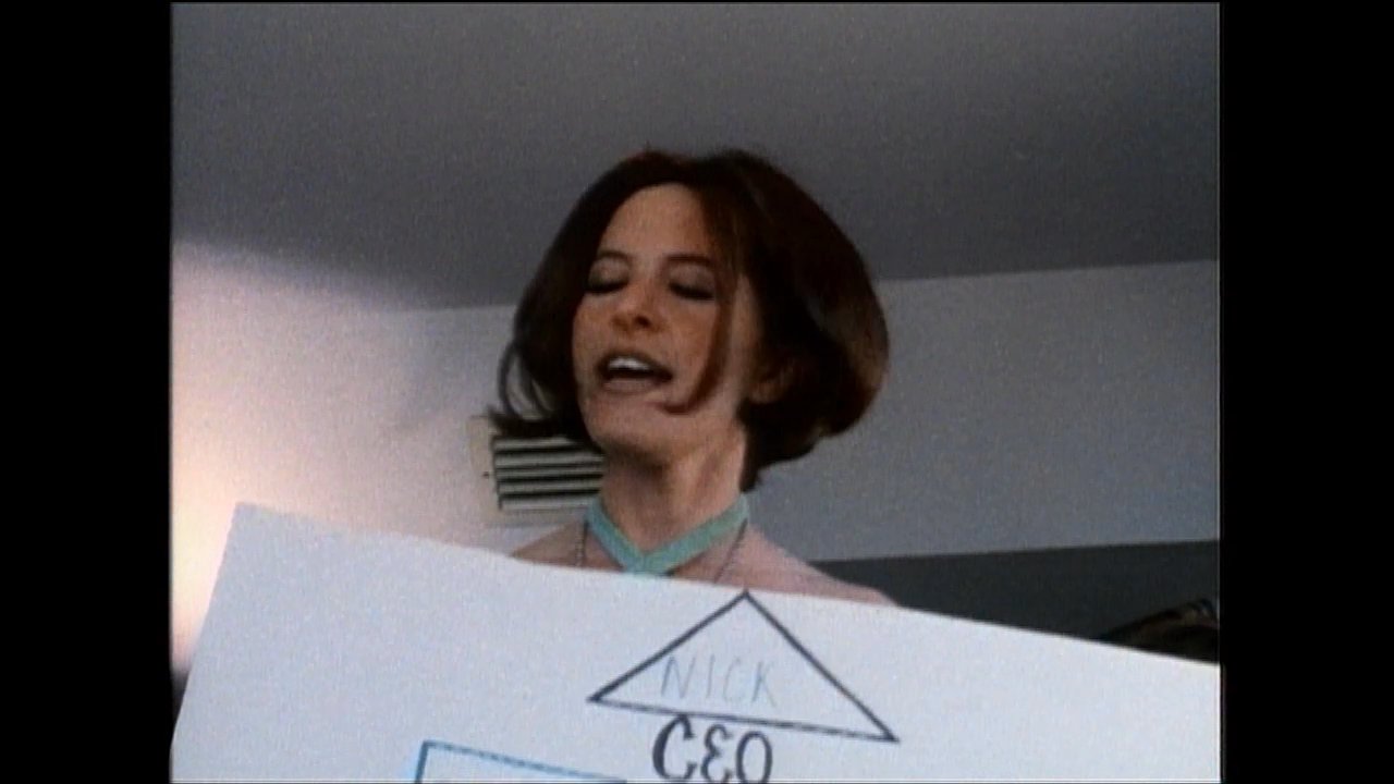 Individuals present a hand-drawn organizational chart identifying roles and management structure while discussing corporate hierarchy. The sequence highlights professional dynamics through a visual display of leadership and reporting lines.