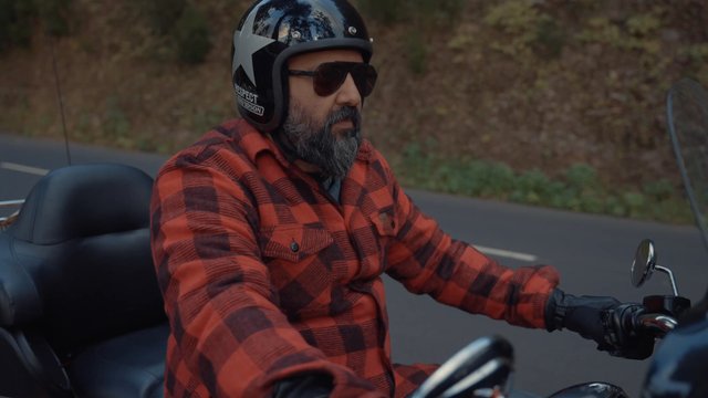 A bearded man twisting a motorcycle throttle and getting ready to hit the road
