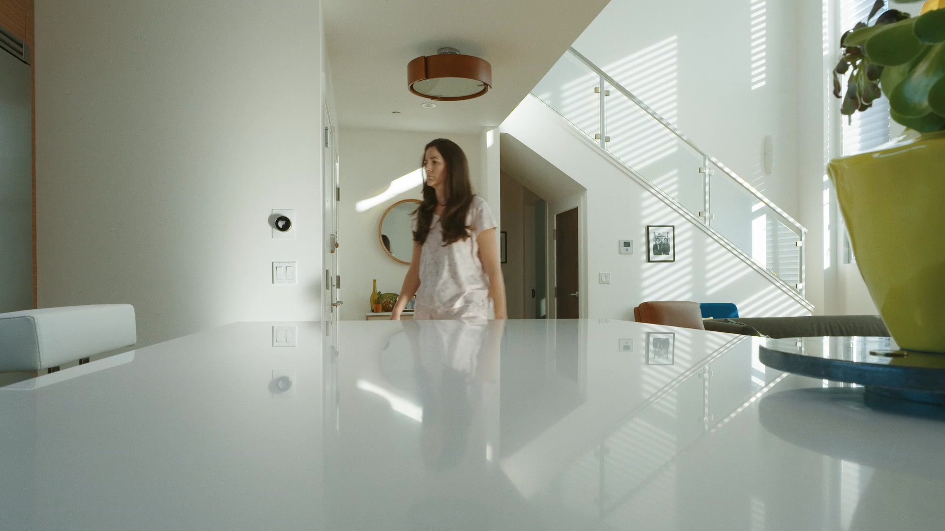 A woman exits a modern residence and transitions to a view of the surrounding city neighborhood, followed by a person jogging down the street.
