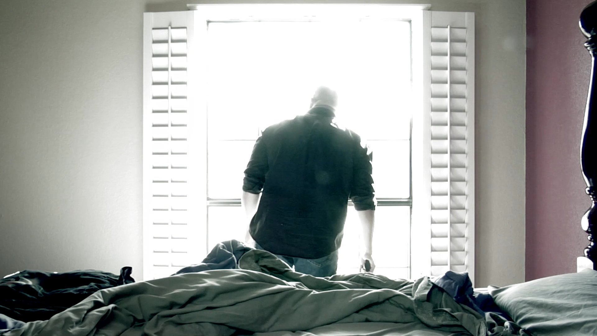 A sequence alternates between perspectives from a moving vehicle on a tree-lined dirt road and a man looking through a bright bedroom window.