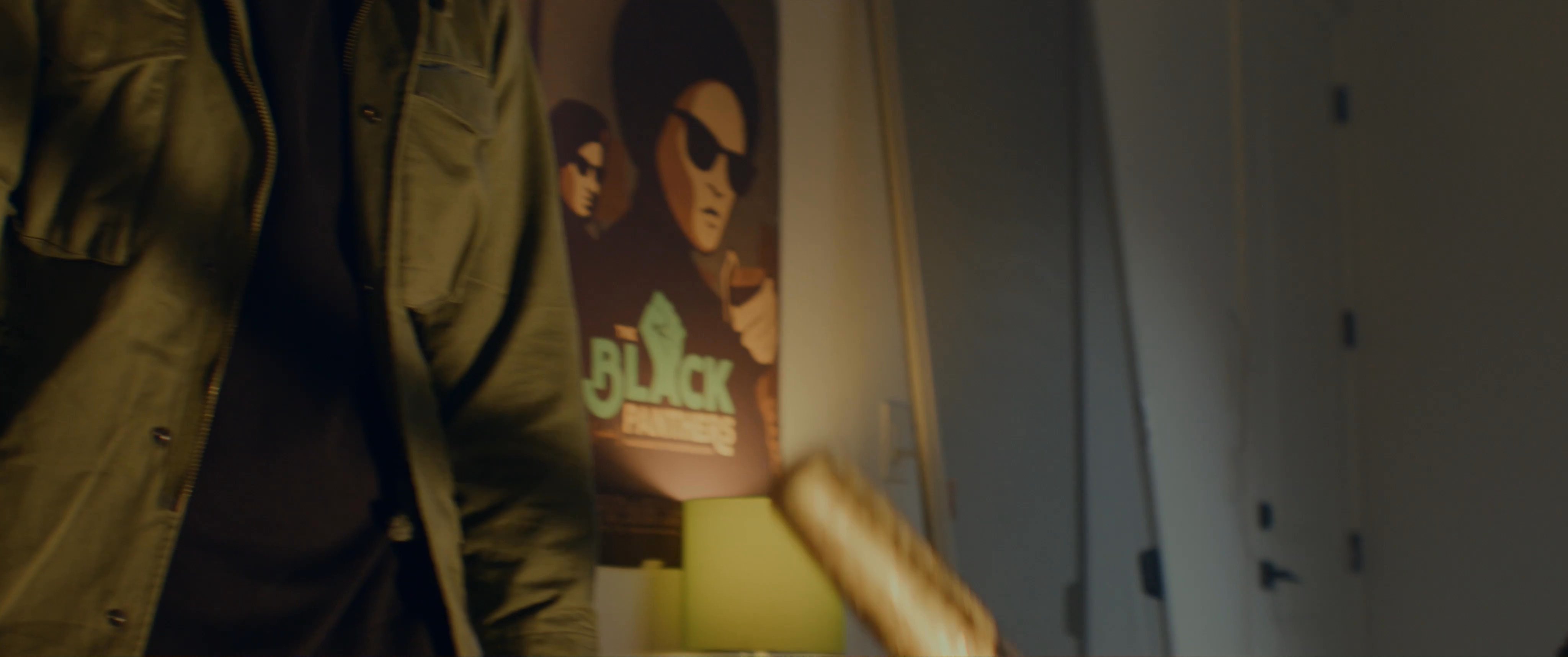 Individuals engage in a tense conversation within a room decorated with revolutionary-themed posters. The interaction culminates in an older woman delivering a firm, gestured directive to the other participants.