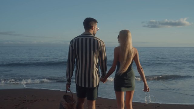 A loving couple holding hands and walking on the beach
