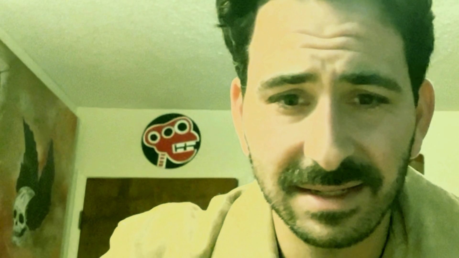 A man with a mustache engages in a serious conversation, exhibiting various facial expressions as he speaks during what appears to be a remote video call. The sequence transitions to a brief shot of a different individual observing the interaction.