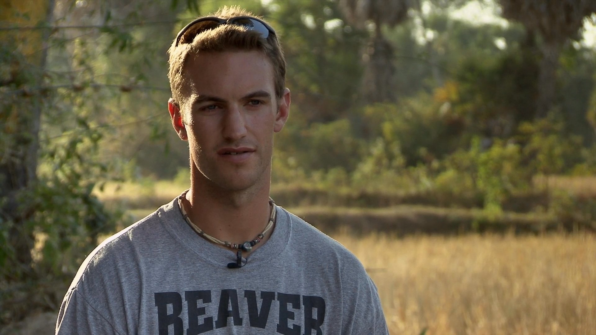 A presenter engages with local villagers in a rural setting, transitioning from a field interview to a lively interaction with a group of young people.