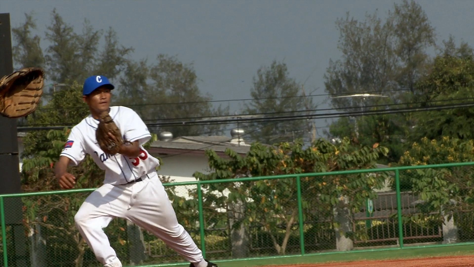 Professional instructors lead a baseball team through coordinated drills and technique coaching on an outdoor field. Players practice fundamental skills in a structured athletic environment.