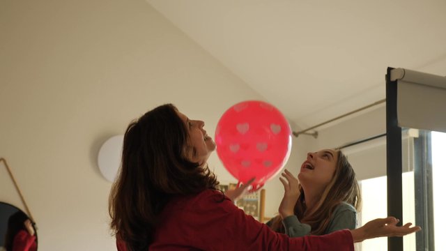Una mamá y una hija juegan con globos de aire