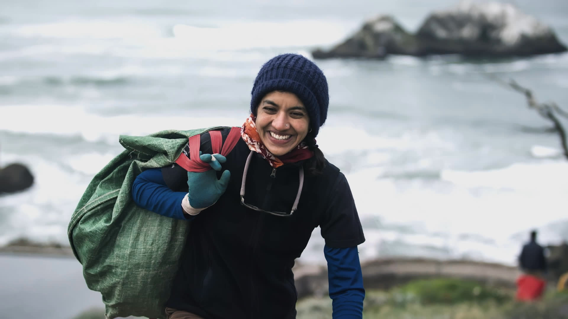 An outdoor traveler appears among snowy peaks and carries a backpack along an icy shore before speaking beside a lake. She reflects on her sensory experiences in nature and her vision of inspiring others to love the natural world.