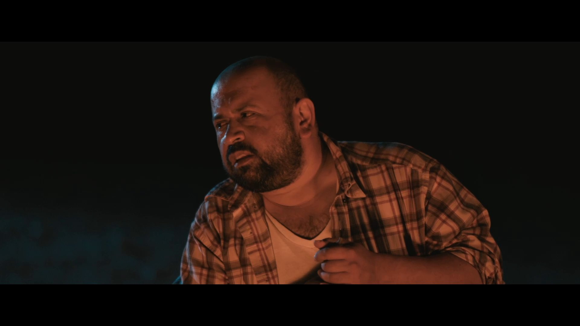 Two men engage in a conversational exchange while sitting outdoors in the dark, discussing whether one has bread.