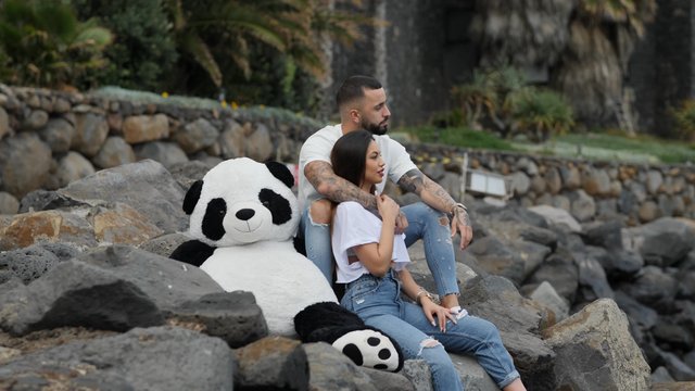 Couple sitting next to a panda toy