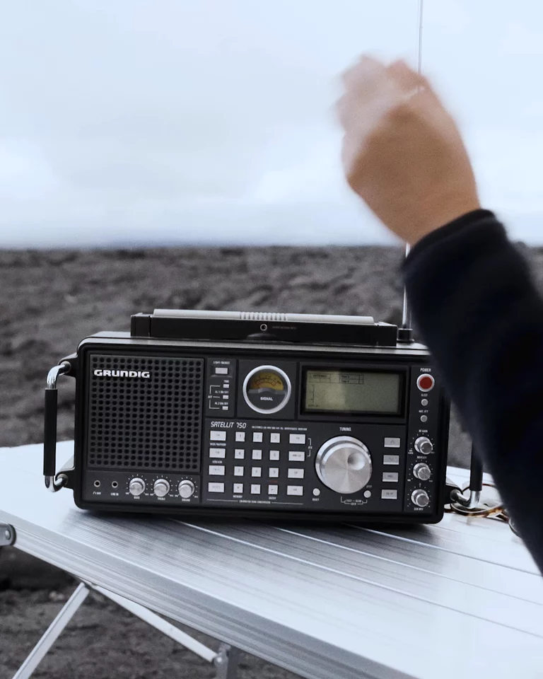 Hand turning dials on portrable radio with lava fields in the background