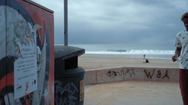 A man throwing garbage into a trash can on the beach