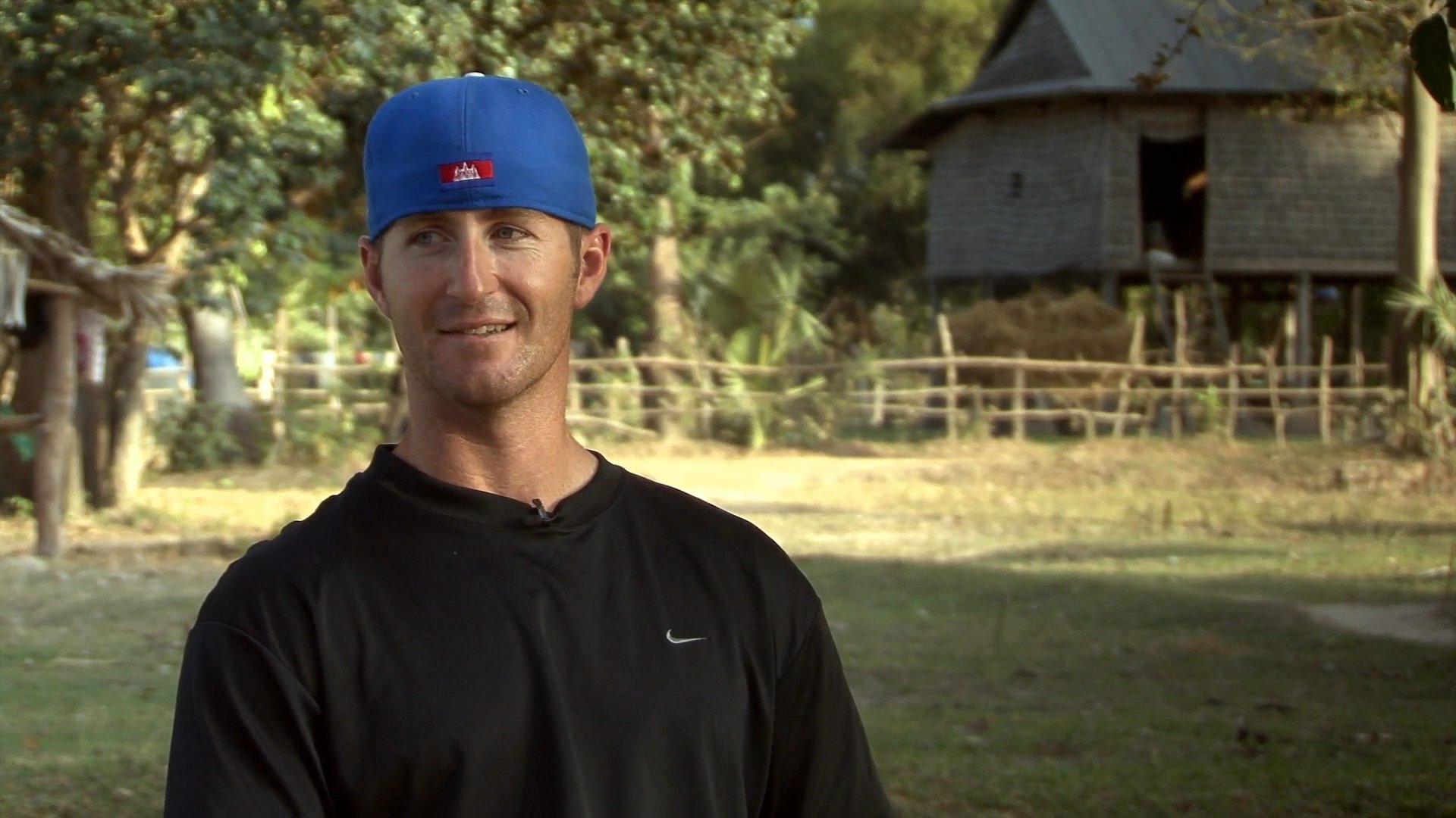 A man shares insights during a field interview situated in a rural village, followed by scenes of children interacting in the local community space.