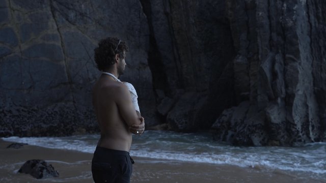 A man with a broken hand standing on the beach