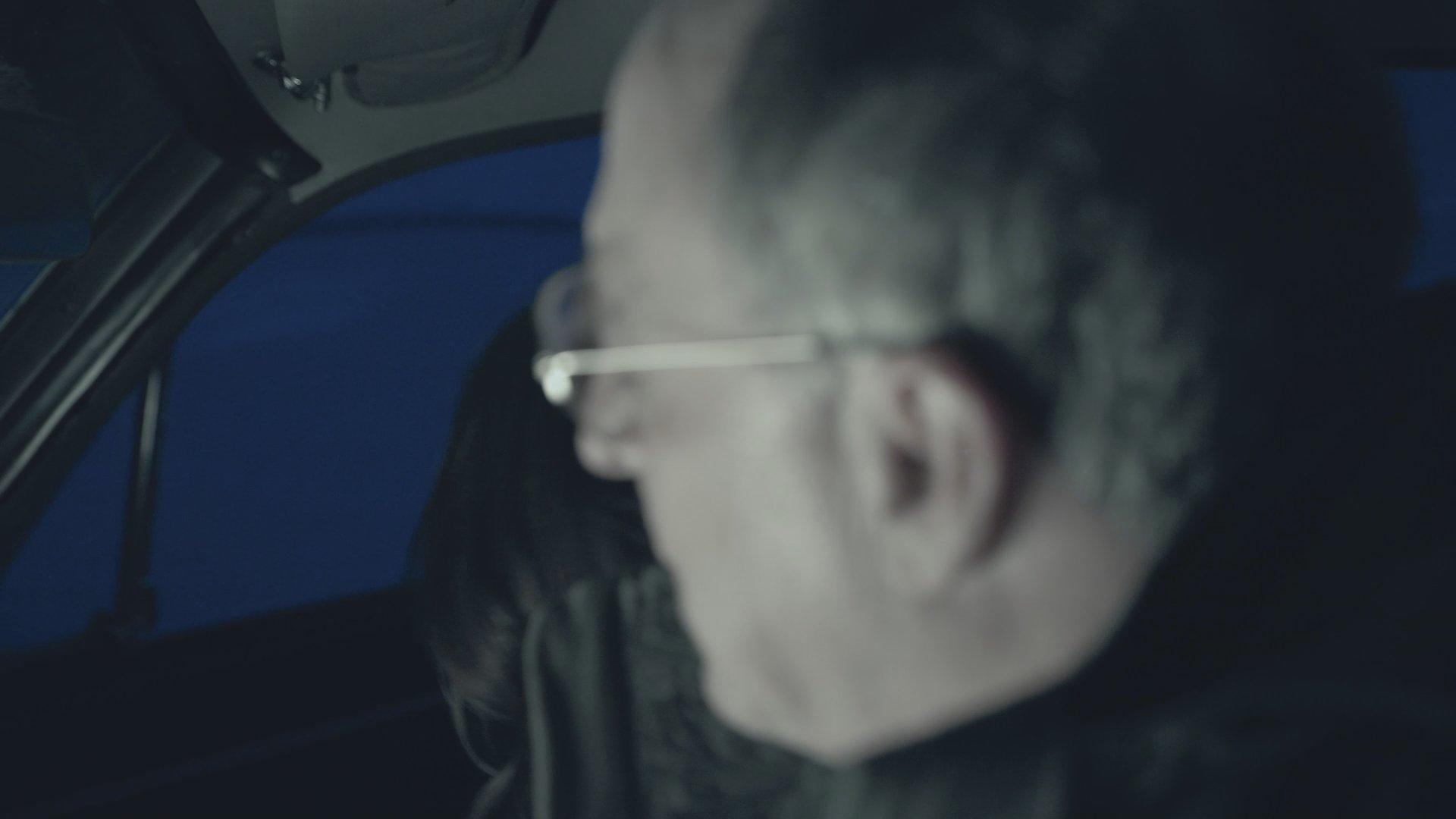 A man and a woman engage in a tense conversation inside a car before both exit the vehicle into a cold, snow-covered landscape.