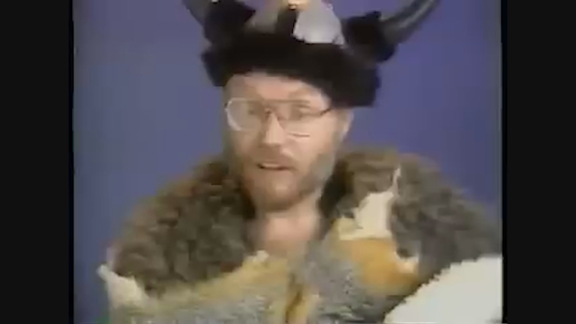A performer cycles through various humorous characters against colorful studio backdrops, utilizing costume changes and exaggerated delivery to deliver a comedic sketch.