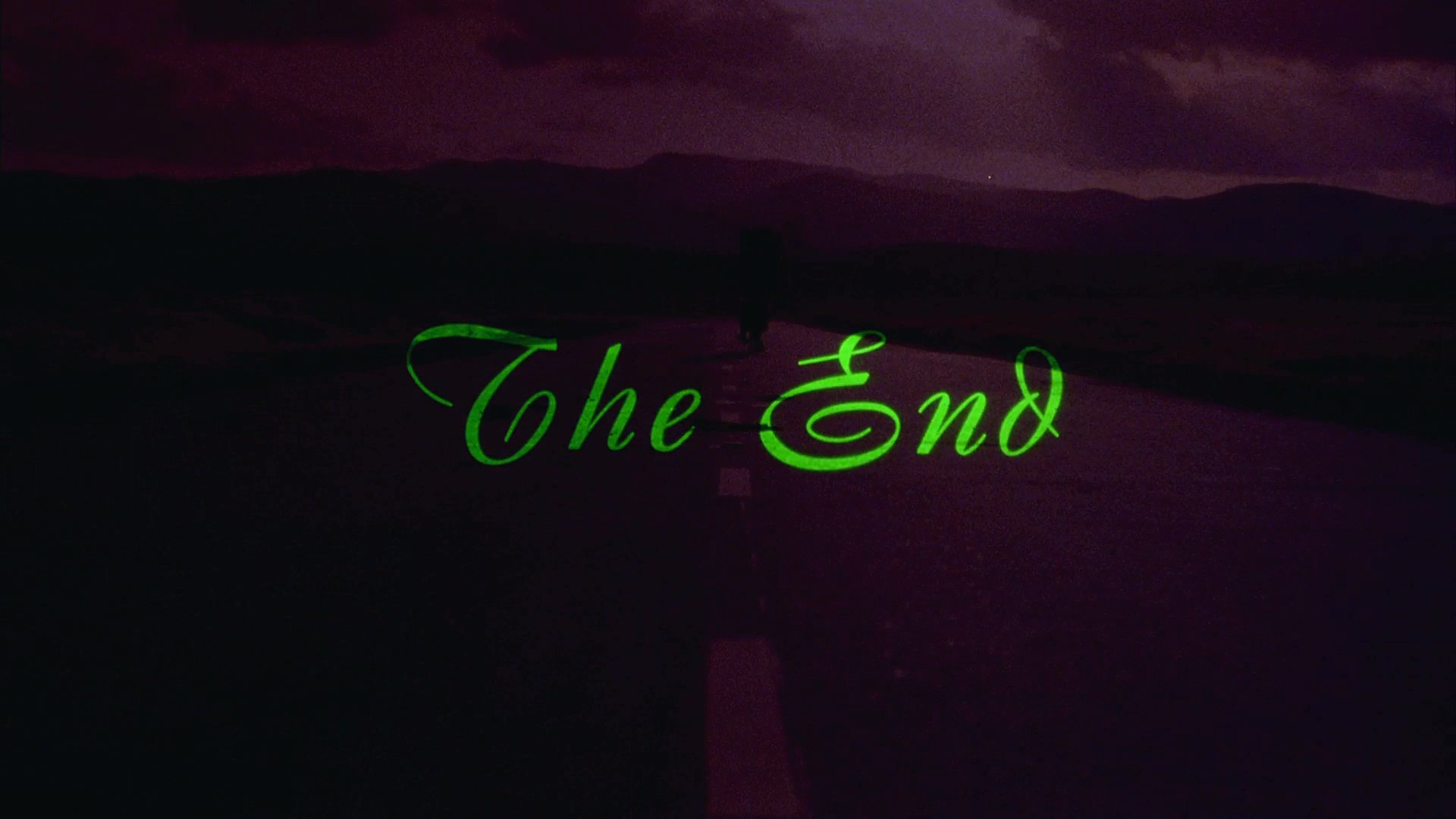 A traveler with a large backpack walks down an empty highway at sunset, moving further away into the distance until the scene fades to a concluding title card.