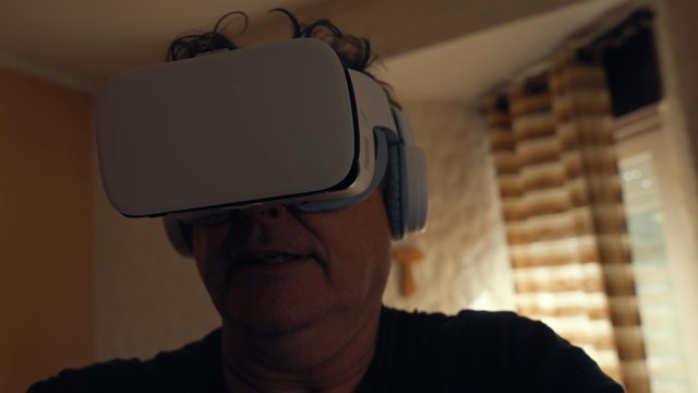 A senior man enthusiastically looking into his VR headset  